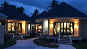 Un moderno resort con dos villas para huéspedes, con amplios ventanales y un área exterior techada.