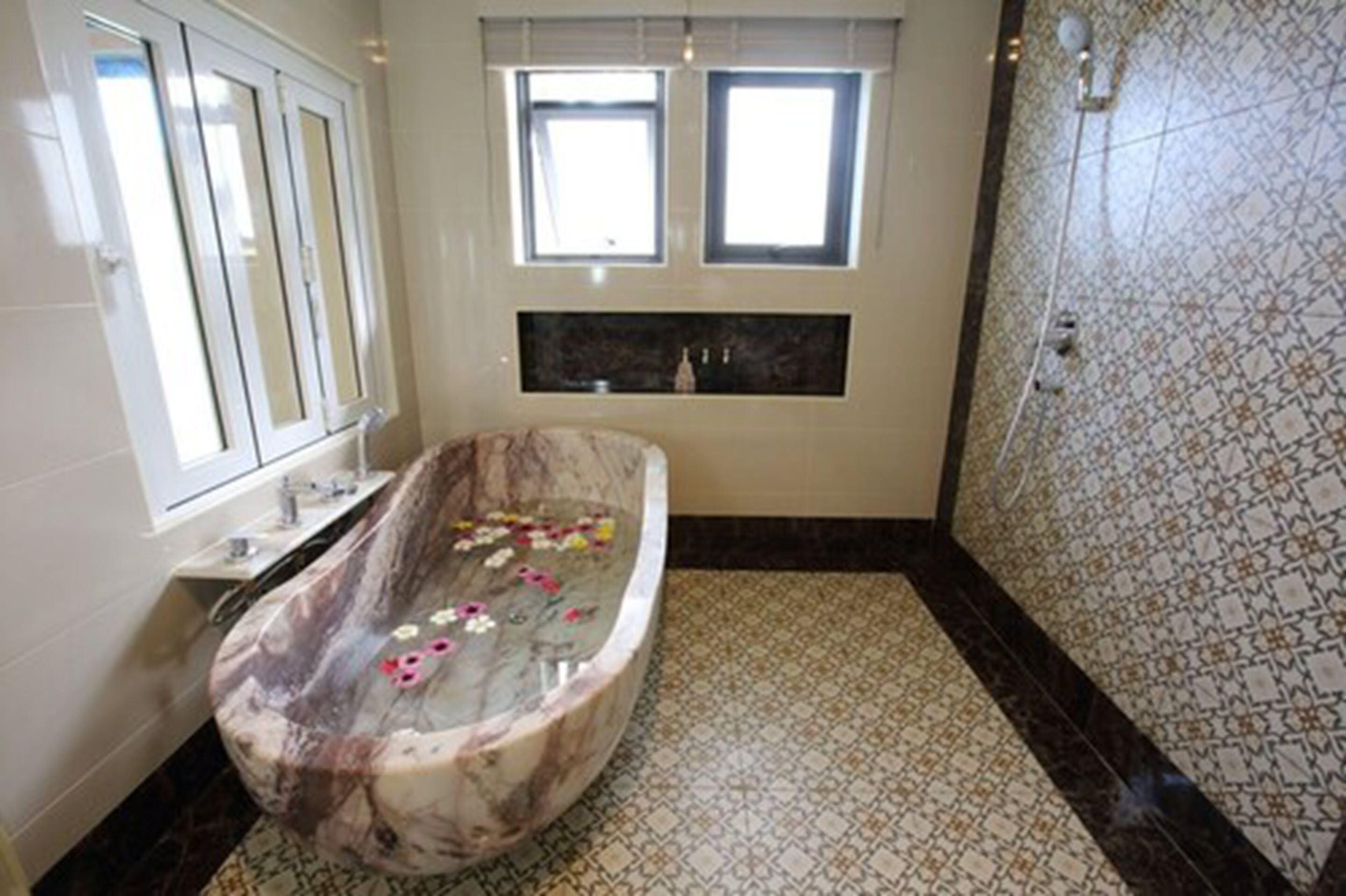 A bathroom with a freestanding bathtub, a window, and a tiled floor.