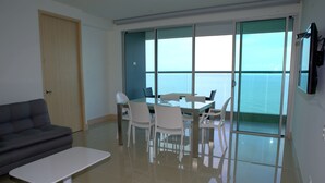 A modern living room with a sofa, a coffee table, and a dining area with chairs and a table. - Murano Elite Aptos Lujo Frente La Playa (Cartagena)