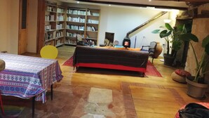 Un salon chaleureux avec un canapé, une table et une bibliothèque remplie de livres.