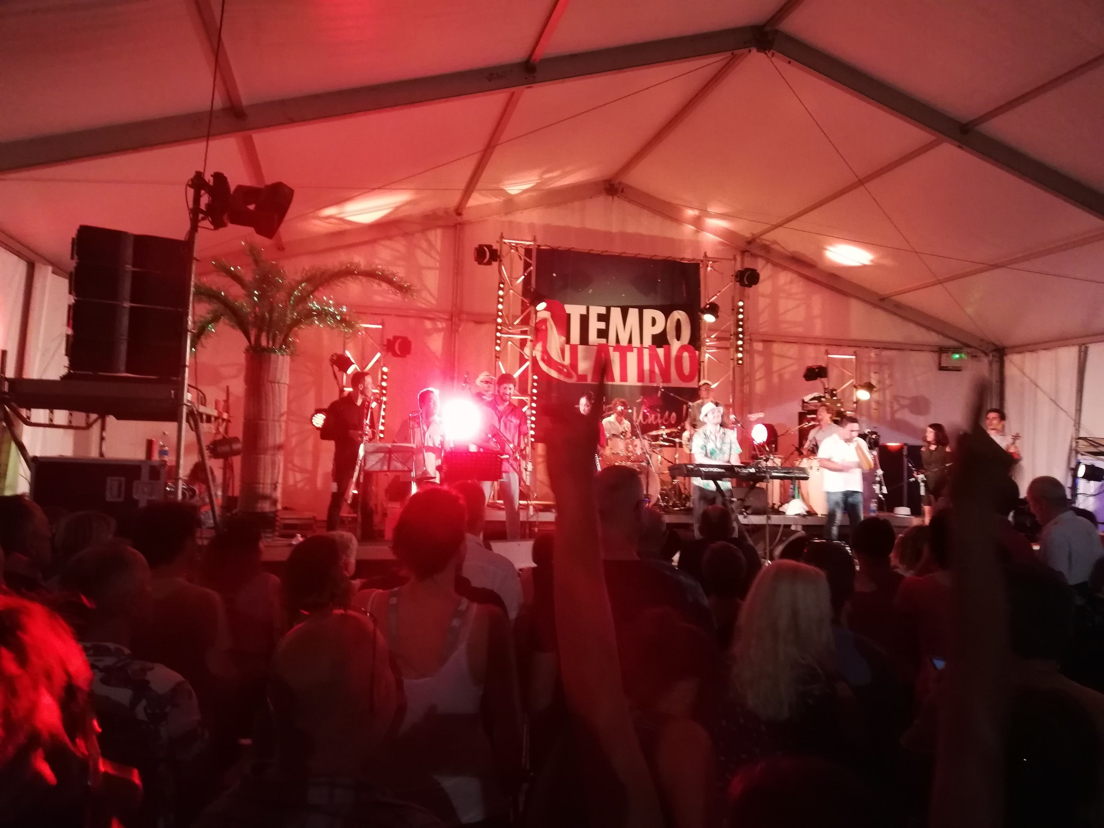 Una banda actuando en un escenario con una carpa encima, bajo un cartel que dice "TEMPO LATINO".