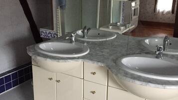 A bathroom with two sinks, a mirror, and a shower.