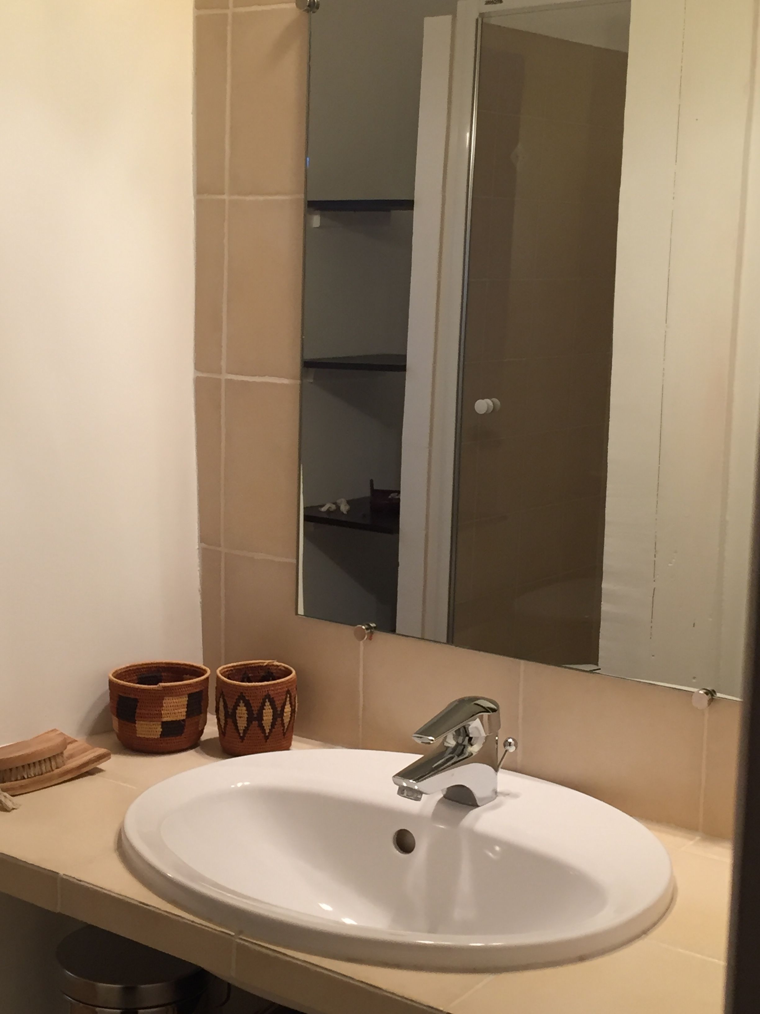 A bathroom with a white sink, two woven baskets, and a mirror above the sink.
