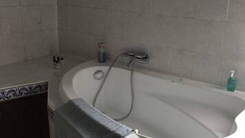 A bathroom with a bathtub, a towel, and a bottle of soap.
