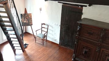 A room with a wooden floor, a staircase, a skylight, a chair, and a wooden cabinet.