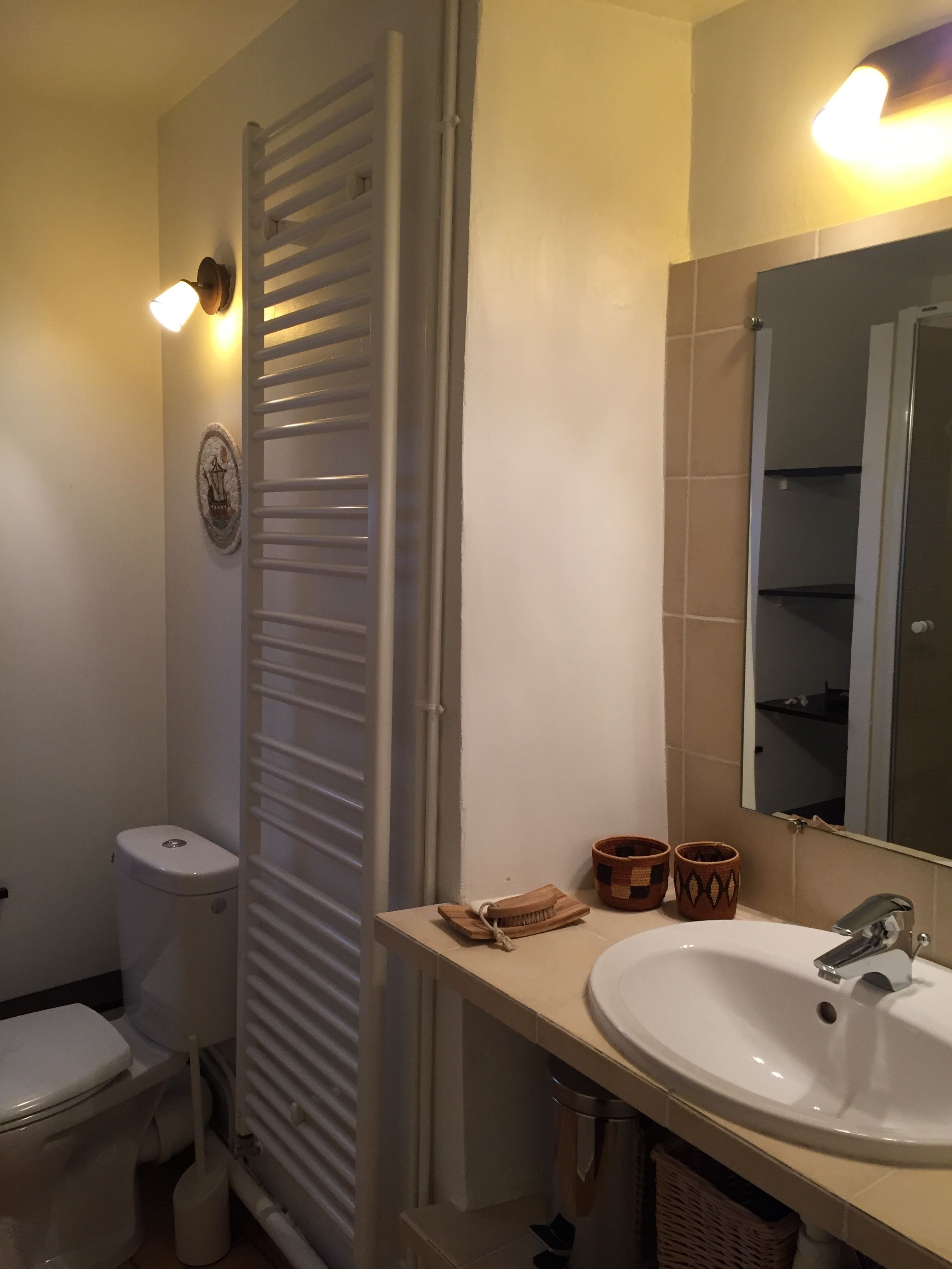 A bathroom with a toilet, a sink, a mirror, and a towel rack.