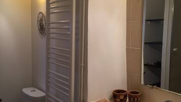 A bathroom with a toilet, a sink, a mirror, and a towel rack.
