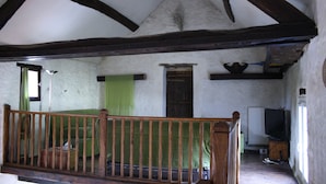 Une pièce avec un escalier en bois, un rideau vert, un radiateur et un téléviseur.