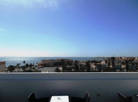A balcony with a view of the sea and buildings.