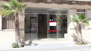 A hotel entrance with a glass door, palm trees, and a tiled walkway. - Boutique Hôtel Albaraka (Dakhla)