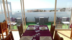 A dining table set for six with a view of the sea and buildings in the background. - Boutique Hôtel Albaraka (Dakhla)