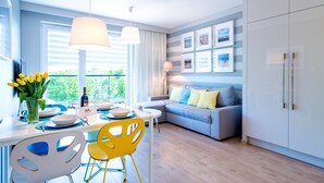 Une cuisine moderne avec un coin repas, comprenant un canapé gris, des chaises jaunes et une table à manger pour quatre personnes.