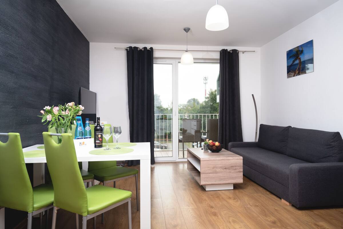 Un salon moderne avec un canapé, une table à manger et des chaises, ainsi qu’un téléviseur.