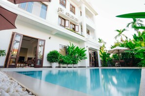 A modern hotel with a swimming pool, outdoor seating, and lush greenery. - Hoi An Lotus Aroma Villa (Da Nang)