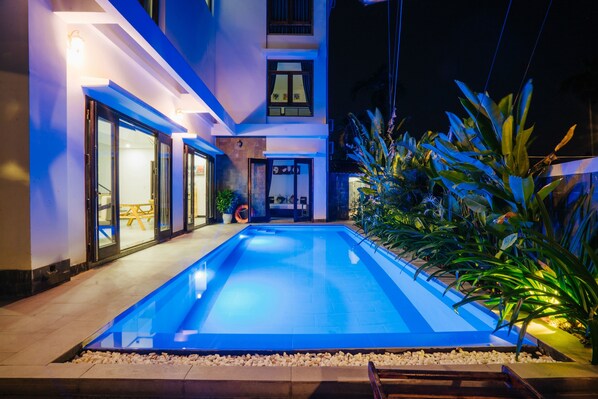 A modern building with a swimming pool, large windows, and outdoor plants. - Hoi An Lotus Aroma Villa (Da Nang)