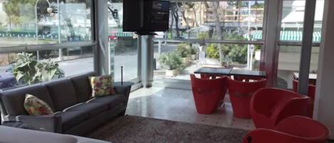 A modern living area with a sofa, red chairs, and a TV.
