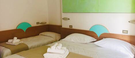 Habitación de hotel con dos camas individuales, cada una con cabecero, un panel de pared verde grande y un corredor de cama.