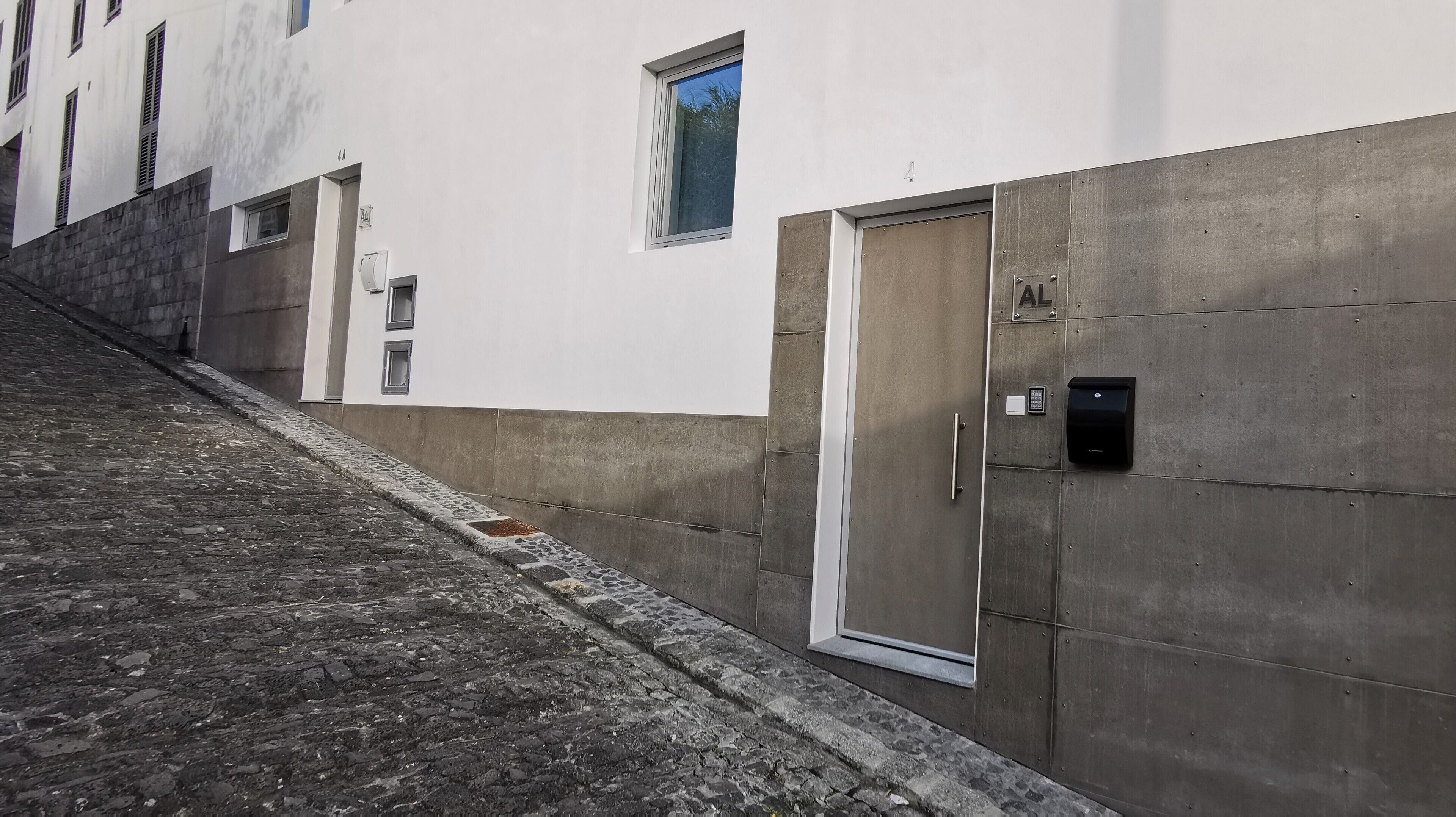 A building with a white facade, a concrete base, and a door with a handle.