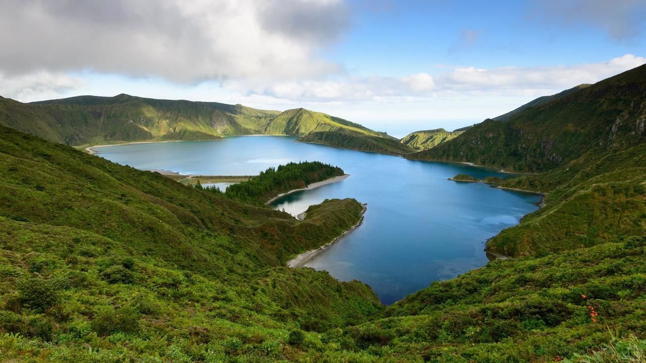 A mountainous landscape with a lake surrounded by lush greenery.