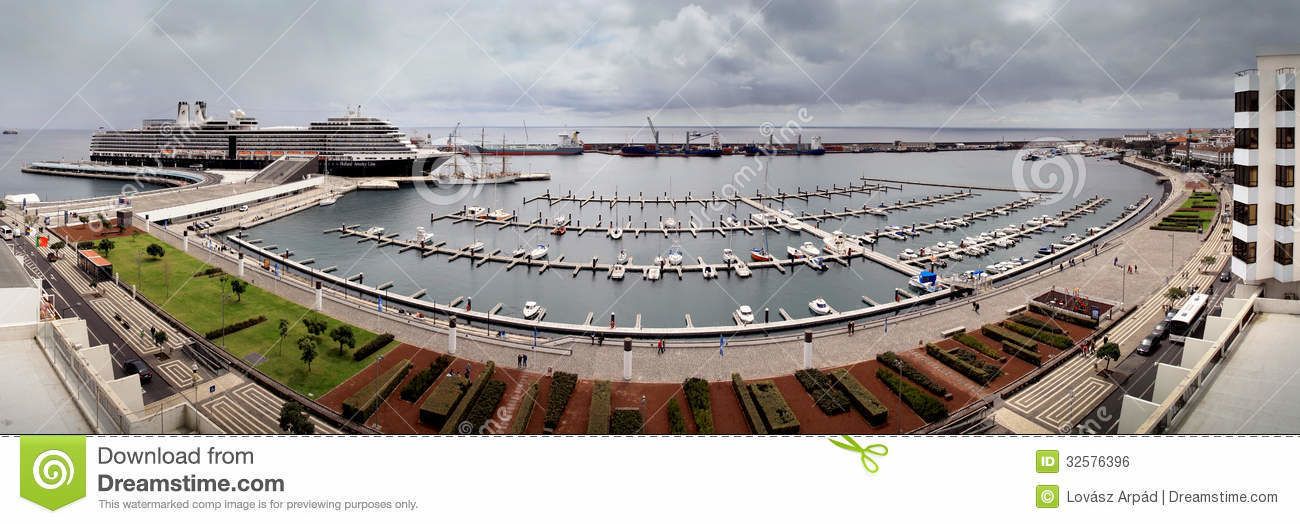 Un port esportiu amb embarcacions amarrades, un gran vaixell de creuer i un edifici de disseny modern.