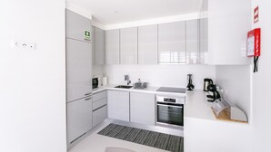 A modern kitchen with white cabinets, stainless steel appliances, and a built-in oven. - Home Azores – Casas da Ladeira (Ponta Delgada)