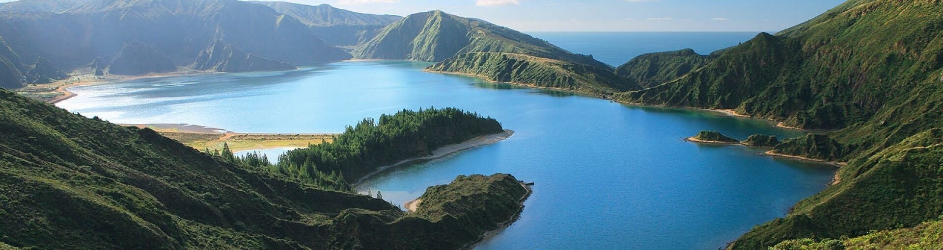 A coastal landscape with a large body of water surrounded by green hills.