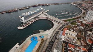 A cruise ship docked at a port with a marina, a swimming pool, and surrounding buildings. - Home Azores – Casas da Ladeira (Ponta Delgada)