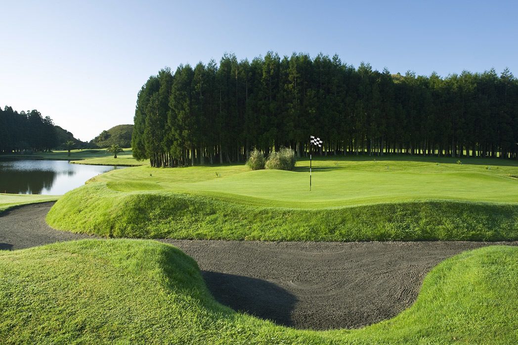 A golf course with a water body, sand bunkers, and a flagstick.