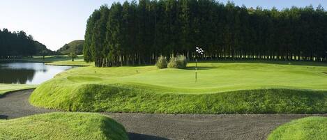 A golf course with a water body, sand bunkers, and a flagstick.