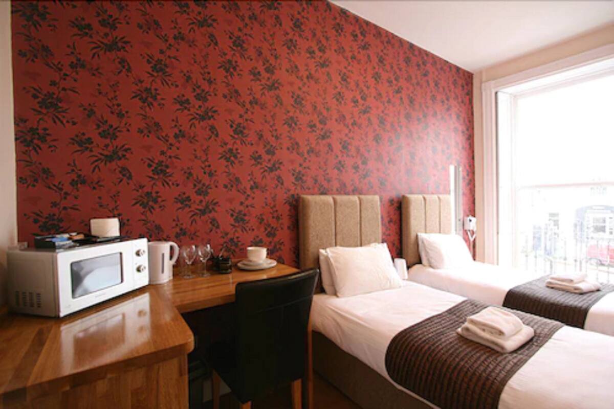 A hotel room with two beds, a desk with a microwave, and a window with a city view.