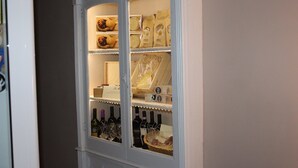 A cabinet with shelves containing wine bottles, bread, and packaged goods. - La Maison (Vallata)