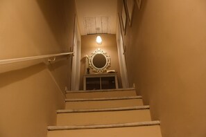 Stairs lead to an upper floor with a handrail and a wall-mounted light fixture.