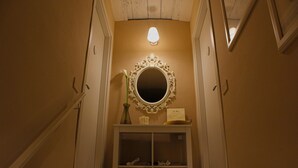 A hallway with a mirror, a vase, and a small shelf with items. - La Maison (Vallata)