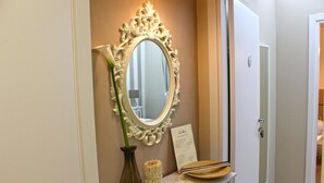 A mirror with an ornate frame, a vase with a green plant, and a menu on a table in a hotel room. - La Maison (Vallata)