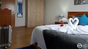 Ett hotellrum med en säng, en garderob i trä, en spegel, ett element och en tavla på väggen.