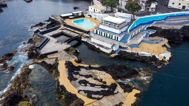 En fastighet vid kusten med en swimmingpool, en byggnad i flera våningar och en klippig strand.