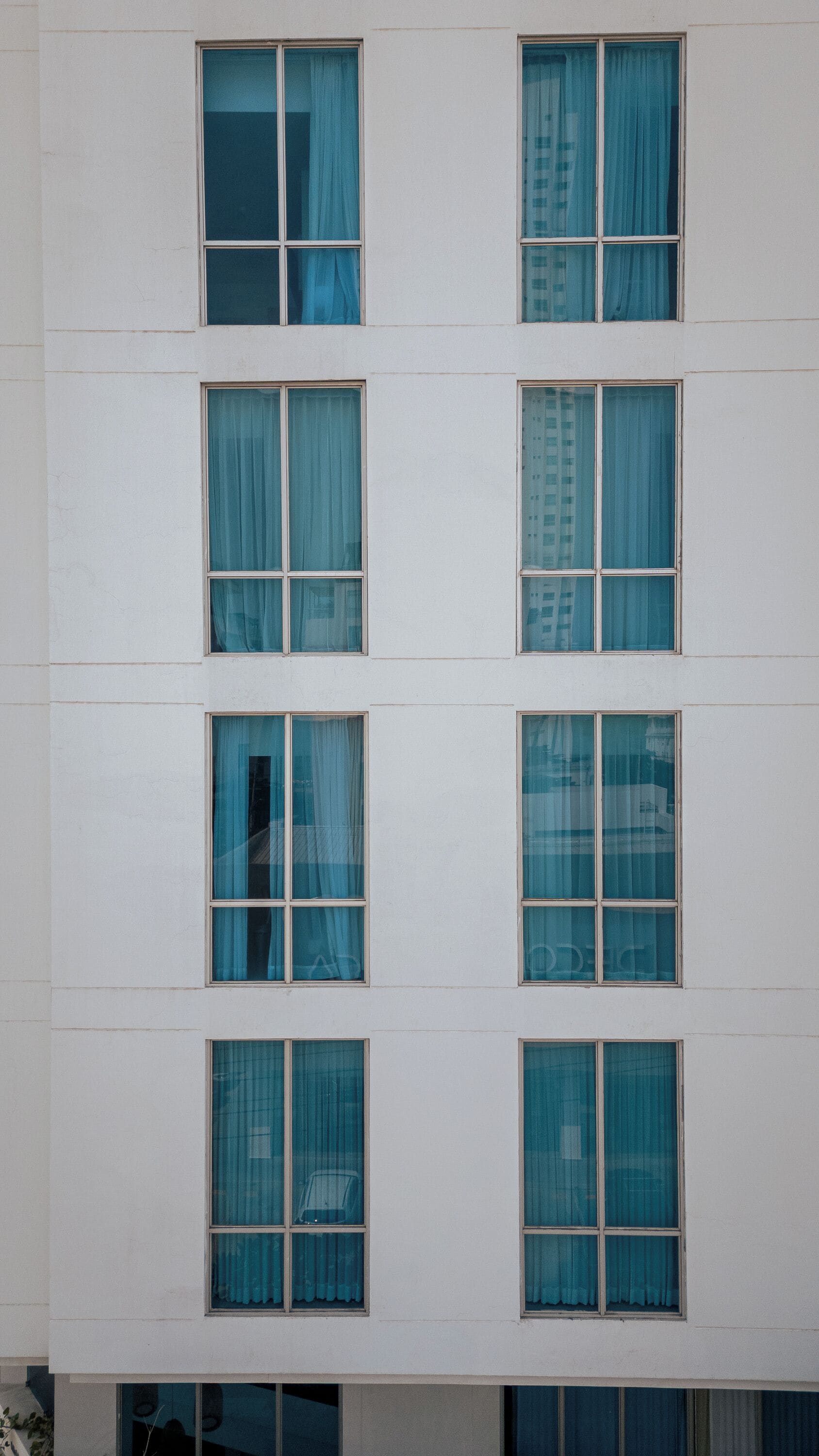 Un immeuble à plusieurs étages, doté d’une façade sobre et de nombreuses fenêtres ornées de rideaux.
