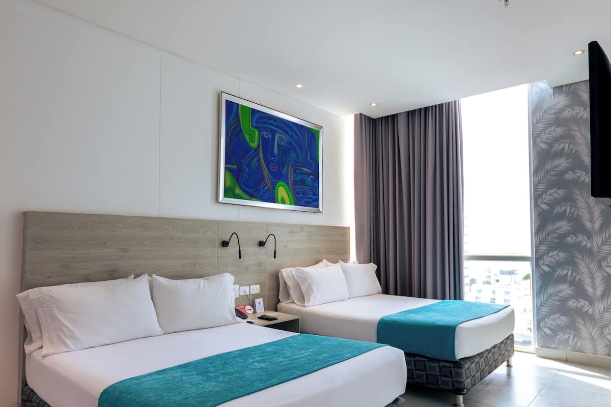 Een hotelkamer met twee bedden, een groot raam, een schilderij aan de muur en uitzicht op de stad.
