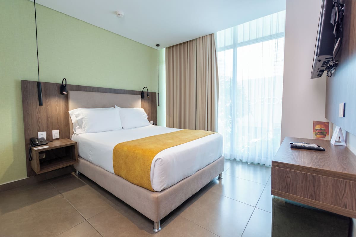Een hotelkamer met een bed, nachtkastje en een bureau met stoel.