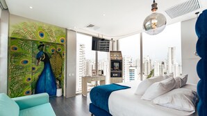 Een moderne slaapkamer met stadszicht, een wand met pauwenmotieven en een groot bed met wit- en blauw beddengoed.