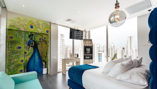 Een moderne slaapkamer met stadszicht, een wand met pauwenmotieven en een groot bed met wit- en blauw beddengoed.
