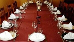 A long dining table set for a formal meal with chairs, plates, glasses, and cutlery. - Hostal la Cerca (Arcones)