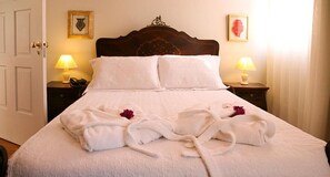 A neatly made bed with white linens and two bathrobes with flowers, two bedside lamps, and a framed picture on the wall. - Casa Manuel Espregueira E Oliveira (Viana do Castelo)