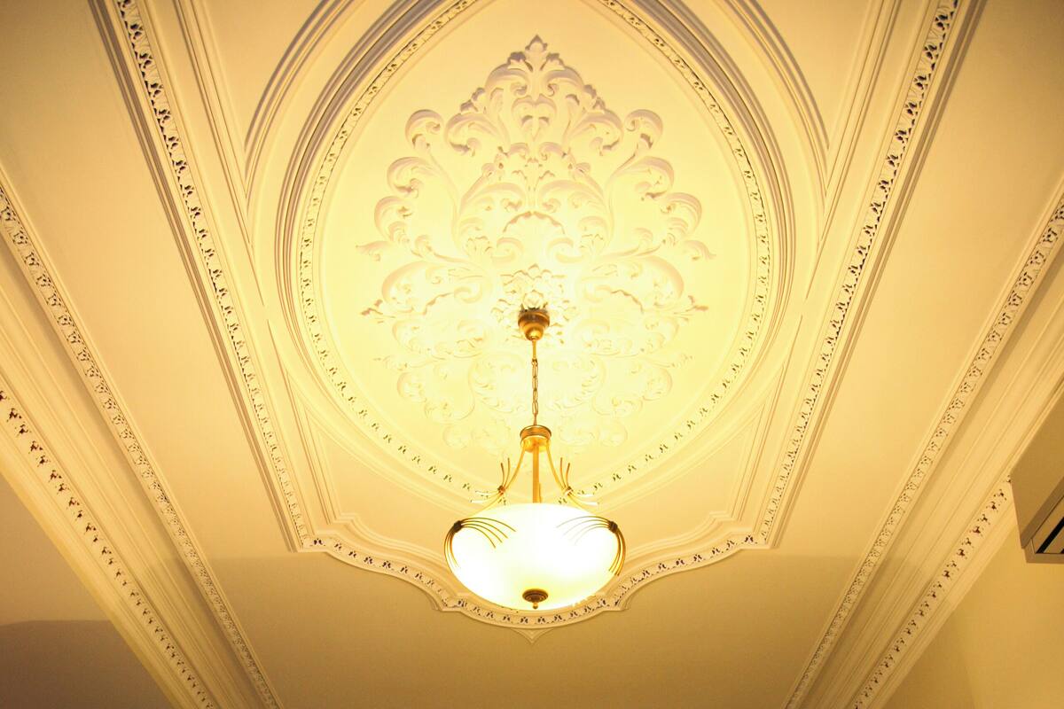 Habitaci ón de hotel con una cama grande, dos lámparas de noche, un cuadro en la pared y un diseño de techo ornamentado.