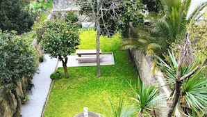 Un jardin bien entretenu, avec une fontaine centrale, entouré d’une variété de plantes et d’arbres.