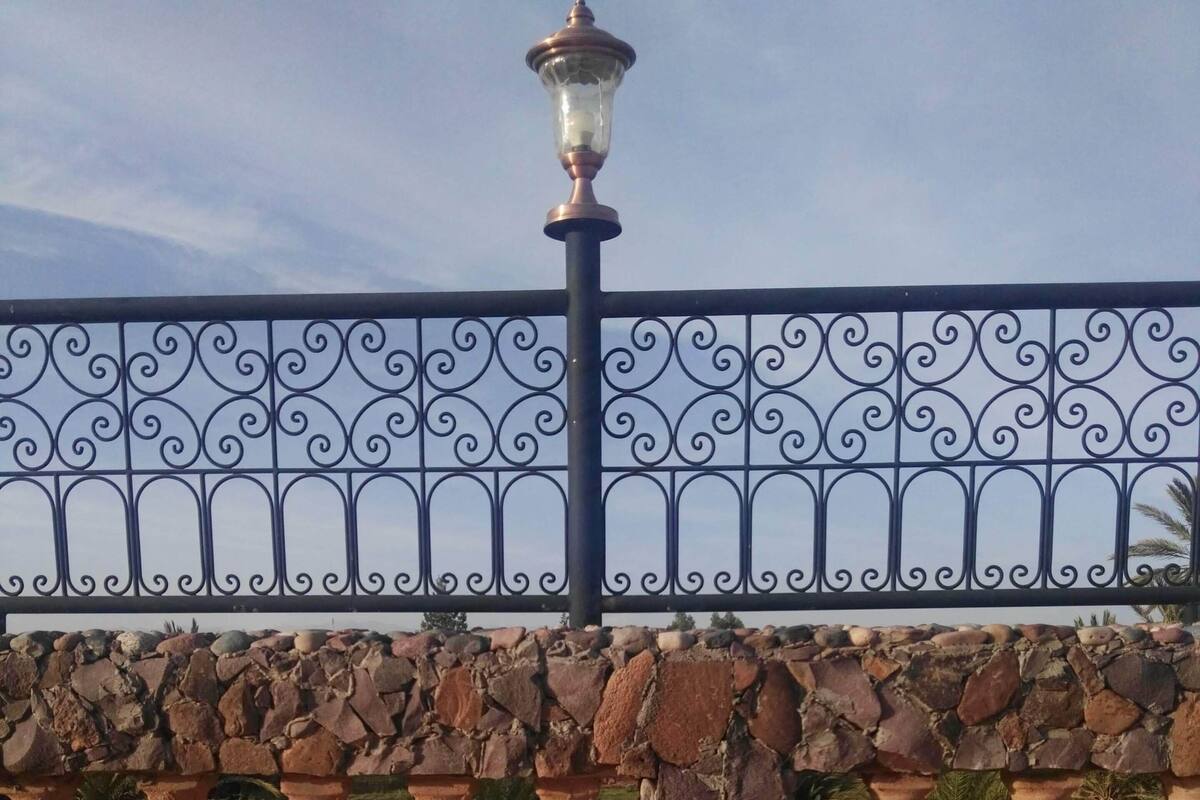 Eine Steinmauer mit Metallgeländer, einer Straßenlaterne und einem Spiegelbild auf einer Oberfläche.