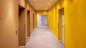 A long, narrow hallway with yellow walls and a carpeted floor. - Hotel Café Nahetal (Gensingen)