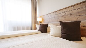 A hotel room with a wooden headboard, a large bed with white bedding, and a window with curtains. - Hotel Café Nahetal (Gensingen)