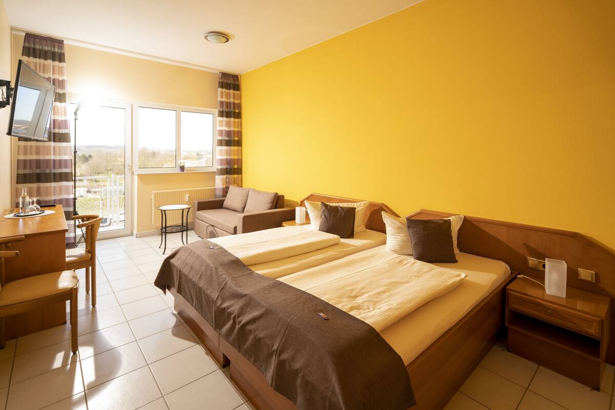 Habitación de hotel con una cama grande, un escritorio, una silla y vistas al exterior.