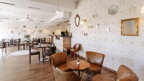A modern dining area with wooden flooring, leather chairs, and a central round table. - Hotel Café Nahetal (Gensingen)